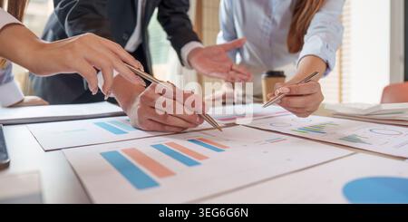 East Asian business professionals collaborating on financial data analysis in office meeting. Stock Photo
