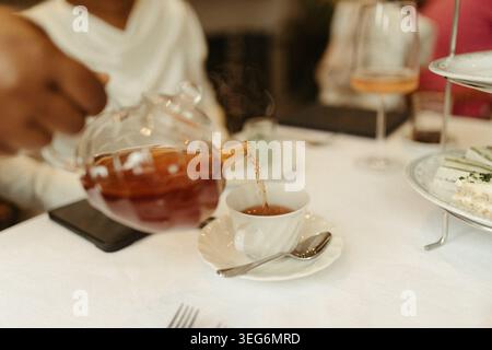 Pouring hot tea from a glass teapot for afternoon tea Stock Photo