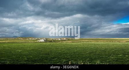 Wide landscape of the Kerry countryside featuring a sunlit pasture and heavy rain clouds at the coast. Stock Photo