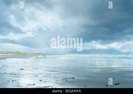 Sunlight breaking through storm clouds over Ballyheigue Strand and the Dingle Mountains in County Kerry Ireland. Stock Photo