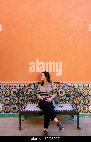 Smiling woman on colorful mosaic bench in Marrakesh, Morocco Stock Photo