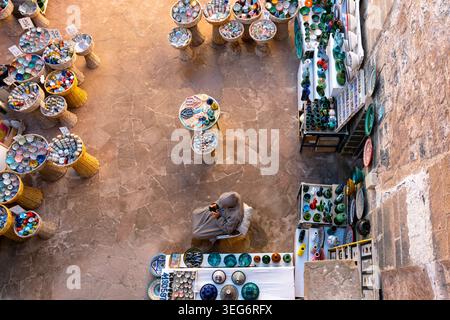 High angle view of man at colorful pottery stall in Essaouira, Morocco Stock Photo