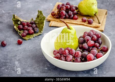 Fresh pears and red grapes arranged in ceramic bowl Stock Photo