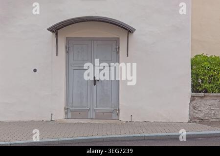 Light blue double doors with decorative arched metal canopy set within a weathered stone wall, Saaremaa, Estonia, Europe. Stock Photo