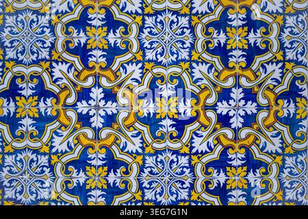 Vibrant blue and yellow Portuguese azulejo tiles with ornate repeating floral and geometric motifs, showcasing traditional hand-painted ceramic crafts Stock Photo