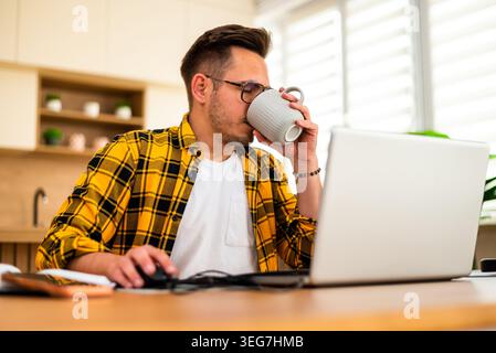 Freelance remote worker is working on his laptop and drinking coffee. Stock Photo