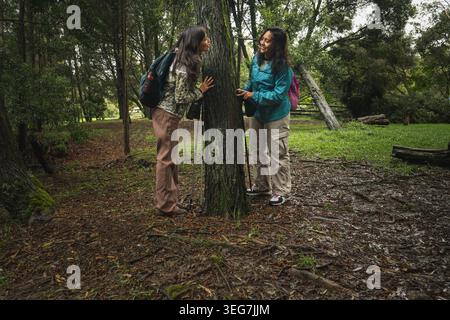 Two women friends enjoying conversation while hiking in the green forest Stock Photo