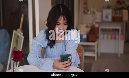 Young asian woman connecting online using smartphone, browsing social media Stock Photo