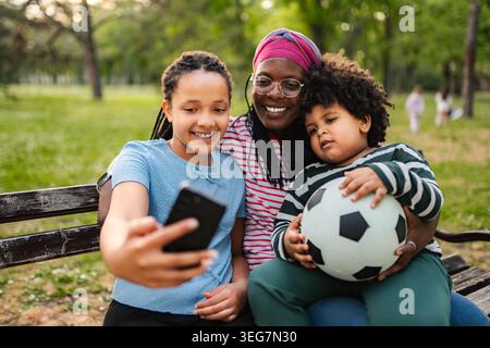 African American mother and children taking park selfie with soccer ball Stock Photo