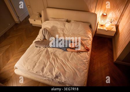 Mindful pause of middle aged woman lying on bed with closed eyes meditating in pleasure thoughts. Stock Photo