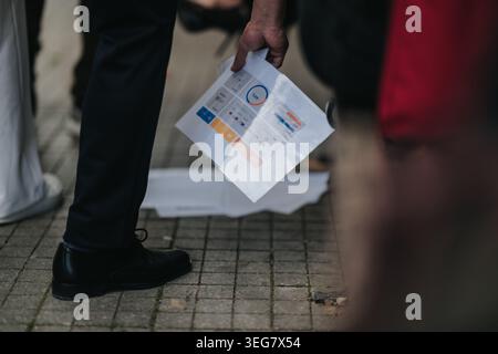 Business people holding a printed report with charts while standing on city pavement during a meeting Stock Photo