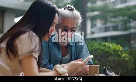 Intergenerational man and woman sharing smartphone, connecting with digital age Stock Photo