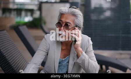 Senior asian man talking on smartphone, communicating, connecting while relaxing Stock Photo