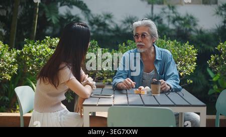 Senior man and young woman having a serious discussion at outdoor cafe Stock Photo