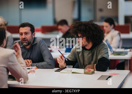 Two colleagues in a focused business meeting discussing notes and ideas at a shared table Stock Photo