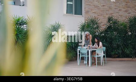 Mentor teaching young asian woman using digital tablet outdoors, sharing experience Stock Photo