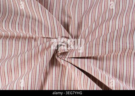 Close up of striped cotton fabric arranged in swirl pattern showing woven textile texture and decorative cloth folds Stock Photo