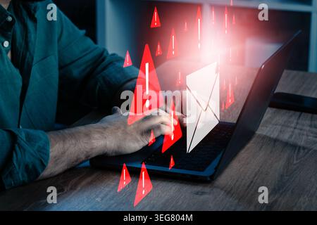 Person typing on laptop while scam messages and warning symbols appear on screen Stock Photo