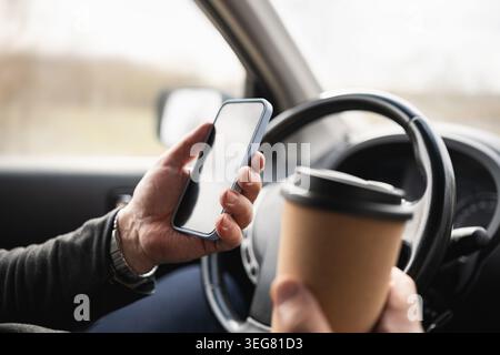 Driver Holding Smartphone And Coffee Cup While Driving Stock Photo
