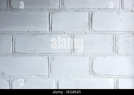 Close-up of a textured white brick wall showcasing distinct mortar joints and surface imperfections, creating a rustic and industrial appearance Stock Photo