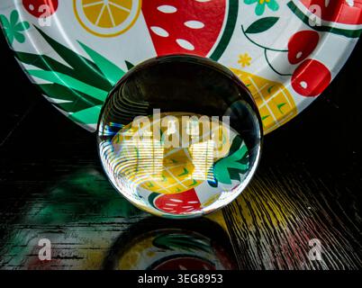 A solid glass ball on a dark surface captures reflected light. Stock Photo