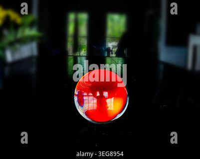 A solid glass ball on a dark surface captures reflected light. Stock Photo