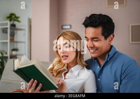 Happy young couple reading a book together at home Stock Photo