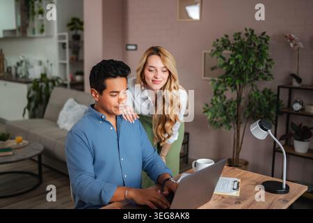 Diverse couple collaborating on laptop in home office Stock Photo