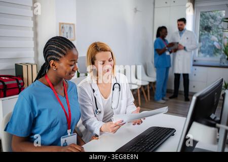 Female medical professionals collaborating on patient records in clinic Stock Photo