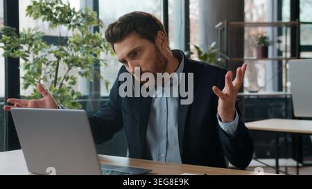 Multitasking Caucasian businessman discuss mobile phone typing laptop in office frustrated male manager business man displeased guy consultant Stock Photo