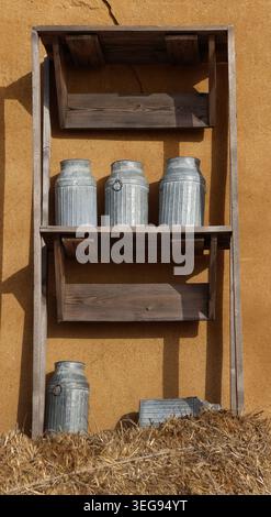 Vintage silver milk pots placed on wooden shelves outdoor. Stock Photo