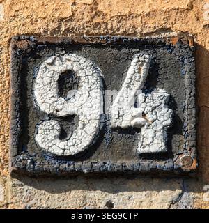Extreme close up of cracked vintage cast iron number 94 sign with detailed grunge paint texture. Stock Photo