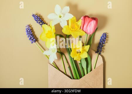 Craft paper envelope with bouquet of bulbous first flowers tulips, daffodils and muscari Stock Photo