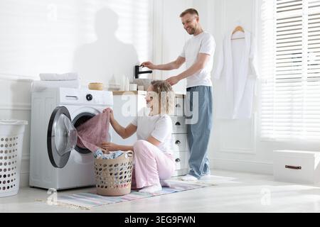 Happy couple doing laundry together at home Stock Photo