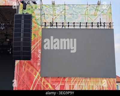 Blank LED screen and line array speaker hanging on an outdoor concert stage with truss and lighting. Professional audiovisual equipment for festival, Stock Photo
