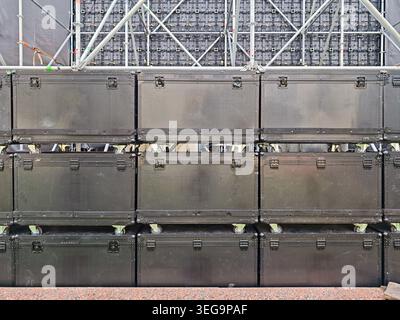 Stacked professional speaker cabinets on wheels in front of LED screen and stage truss during concert setup. Audio equipment for live event production Stock Photo