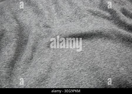 Crumpled grey melange jersey fabric texture with soft waves and shadows. Stock Photo