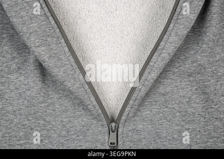 Close-up of a metal zipper half-open on grey melange hoodie fabric. Stock Photo