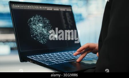 Data center female programmer using AI LLM model on laptop to optimize equipment rigs. Woman in server hub using large language model neural network technology to adjust system parameters Stock Photo