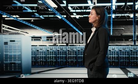 Data center manager inspecting equipment rigs with blue wireframe mesh, VFX compositing. IT expert walking in server hub, looking at hardware augmented reality simulation overlay Stock Photo