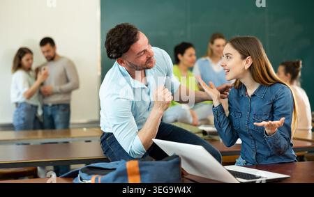 Man and woman students having small talk in classroom Stock Photo