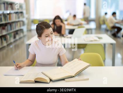 Female student sitting at table and writing Stock Photo