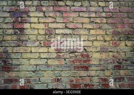 Time worn brick wall with hints of old paint in greens and blues Stock Photo