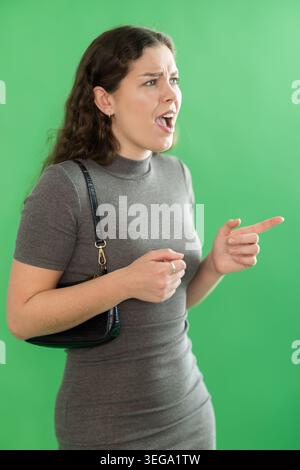 Young woman angry and yelling in front of green screen Stock Photo