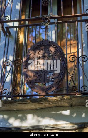 Rustic iron balcony sign with heraldic crest on barred window in Villa del Arco showing traditional Spanish village architecture and warm sunlight Stock Photo