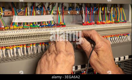Electrical engineer using a circuit tester to check connections on connectors on a building management system. Electrical contractor inspecting a cont Stock Photo