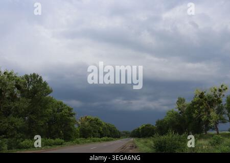Dramatic storm clouds over rural asphalt road in central Ukraine before summer thunderstorm Stock Photo