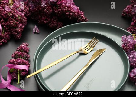 Beautiful table setting with lilac flowers on black background, closeup Stock Photo