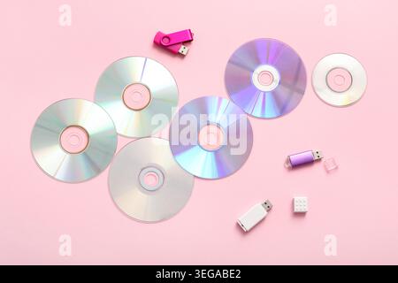 CD disks and USB flash drives on pink background Stock Photo