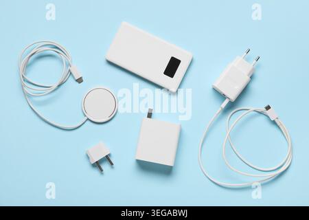 Different modern chargers, power adapters, plug head and USB cables on blue background Stock Photo